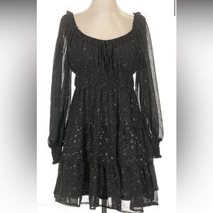 A black dress with sheer sleeves and has gold star detailing all over the dress